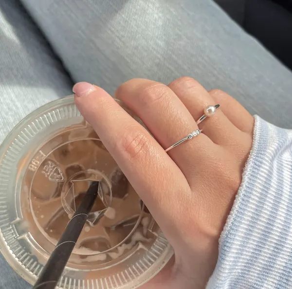 Hand wearing silver rings holding iced coffee